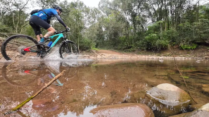Ciclista atravessando o riozinho na Trilha da Eletrosul